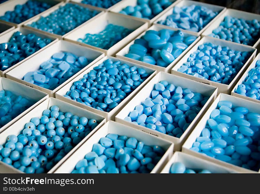 Arrayed boxes containing different types of blue beads. Narrow DoF.