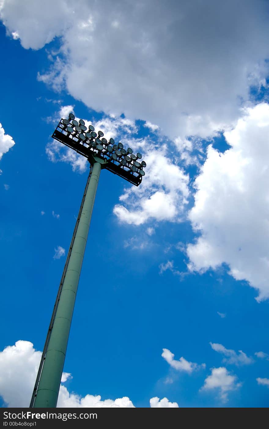 Stadium  lights with blue sky and clouds above. Stadium  lights with blue sky and clouds above.