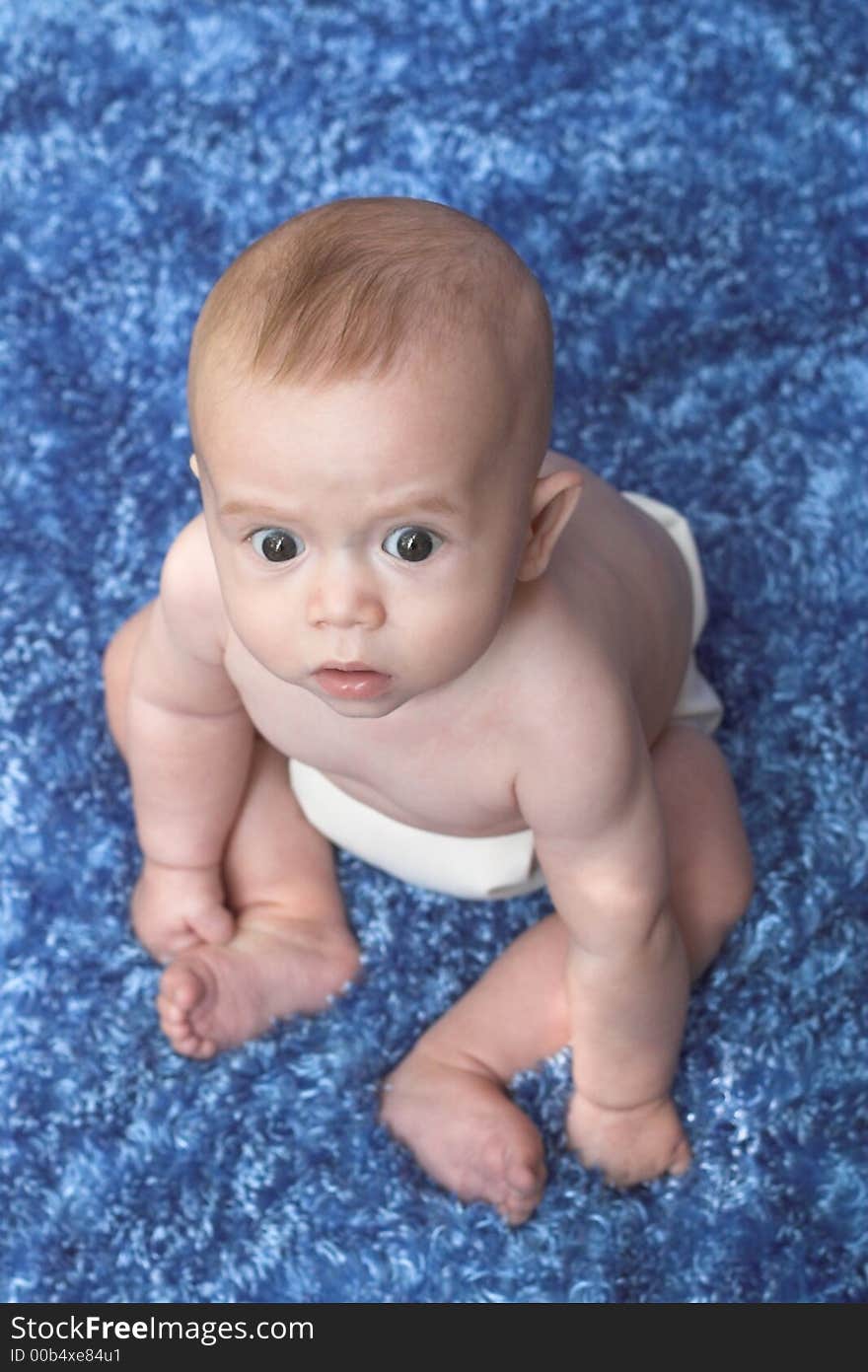 Image of sitting baby, looking up at the camera. Image of sitting baby, looking up at the camera