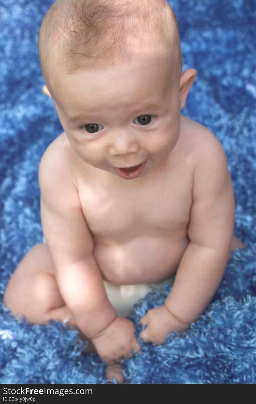 Image of smiling baby boy sitting on a blue blanket