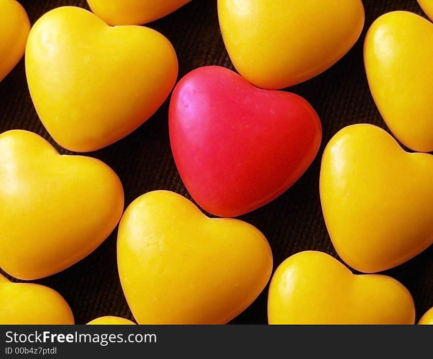 Pink candy heart surrounded by yellow hearts.