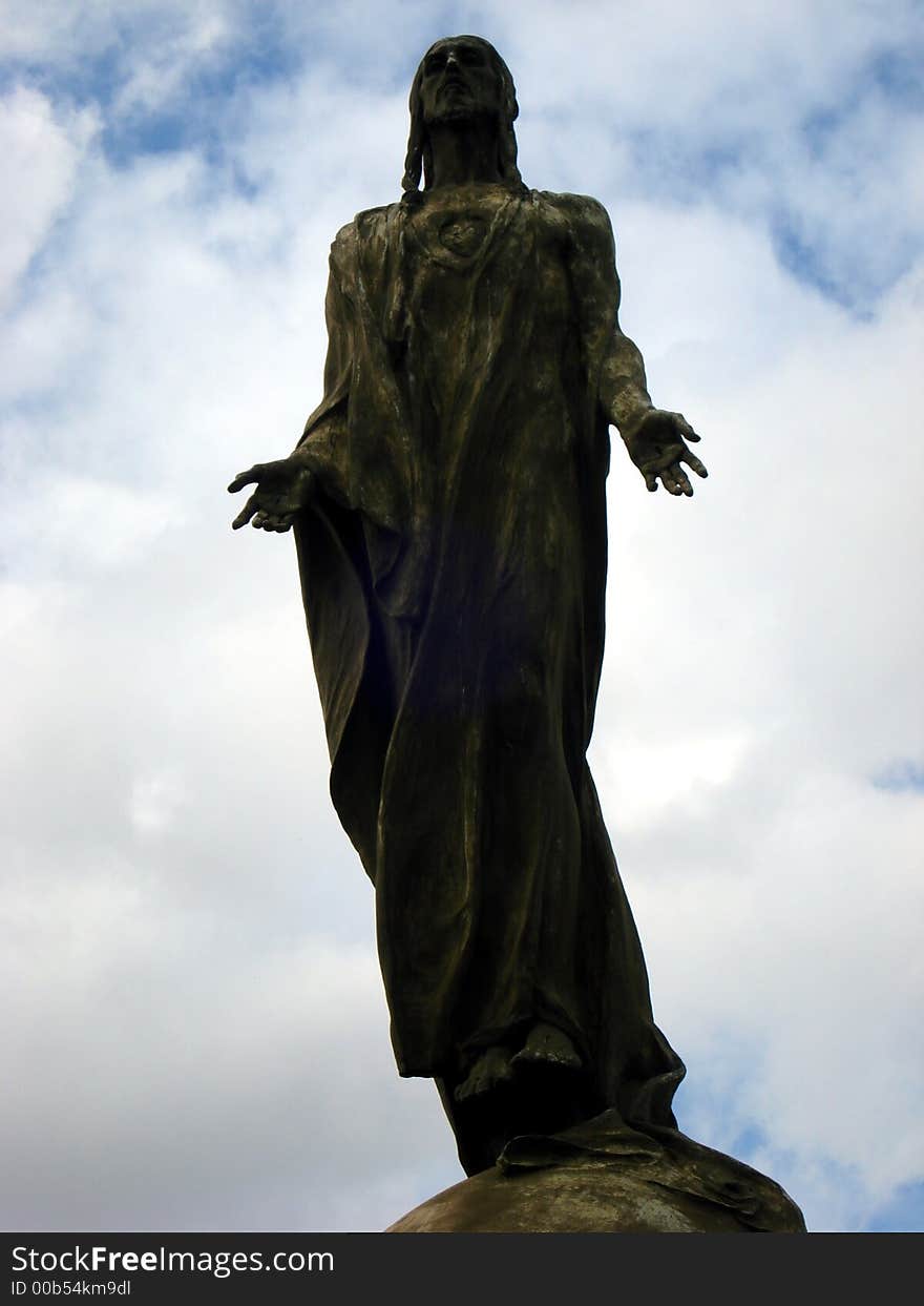 A bronze sculpture of Jesus on air over a cloudy sky. A bronze sculpture of Jesus on air over a cloudy sky