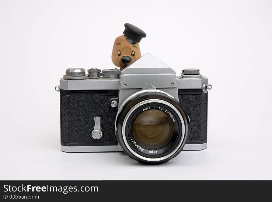 Vintage 35 mm camera pointing at viewer with a small wood model bear as photographer. Vintage 35 mm camera pointing at viewer with a small wood model bear as photographer