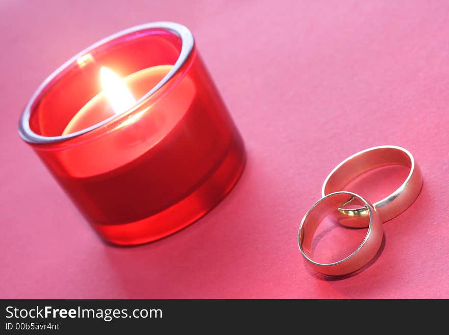 Gold wedding rings with red burning candle. Gold wedding rings with red burning candle