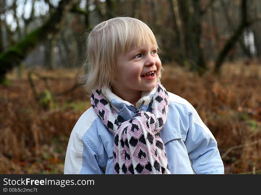 A little girl in a forest smiling. A little girl in a forest smiling