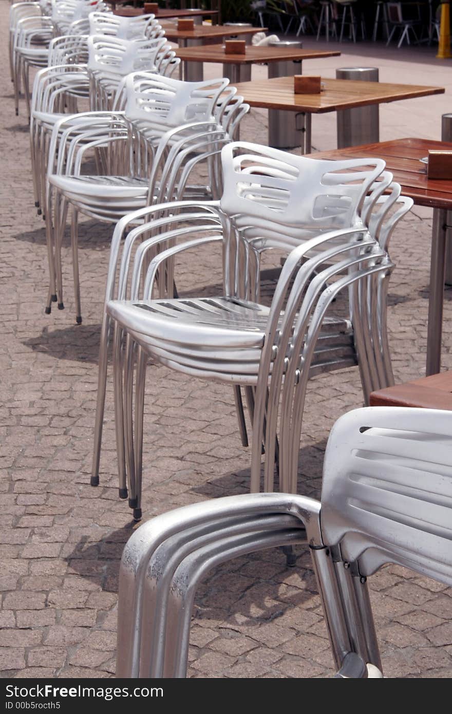 Stacked Silver Chairs In A Row At An Outdoor Restaurant