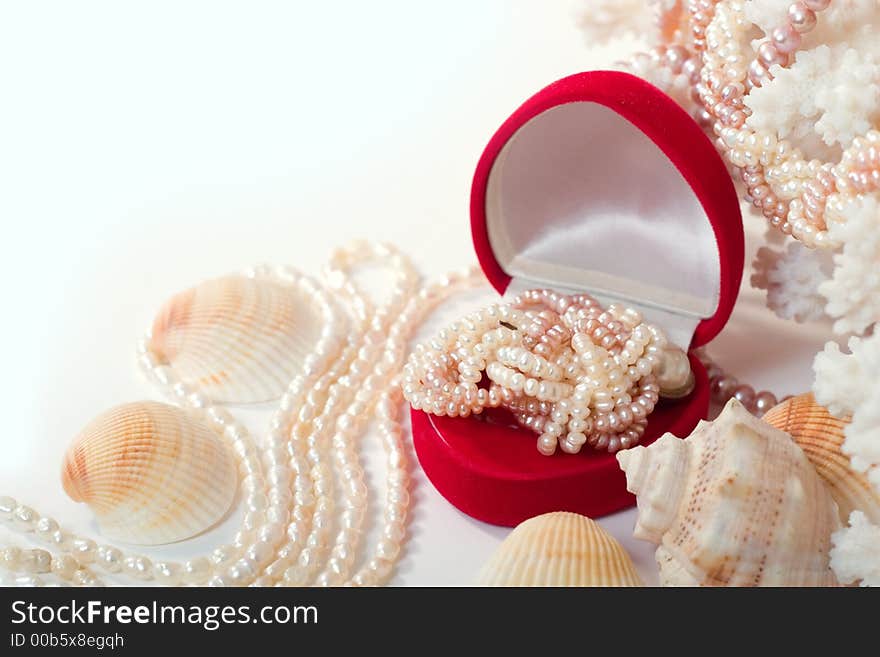 Shells, corals and heart-shaped red box with shiny pearl necklace. With copy space on white background. Shells, corals and heart-shaped red box with shiny pearl necklace. With copy space on white background.