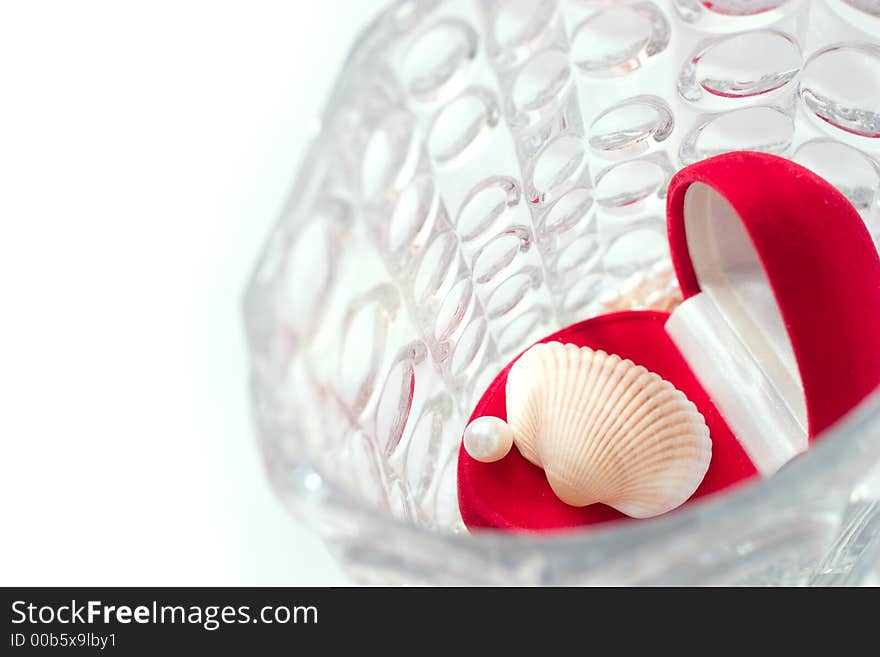 Red box with white pearl and shell in a crystal vase. Focal point is on the pearl. Copy space is on the left side of image. Red box with white pearl and shell in a crystal vase. Focal point is on the pearl. Copy space is on the left side of image