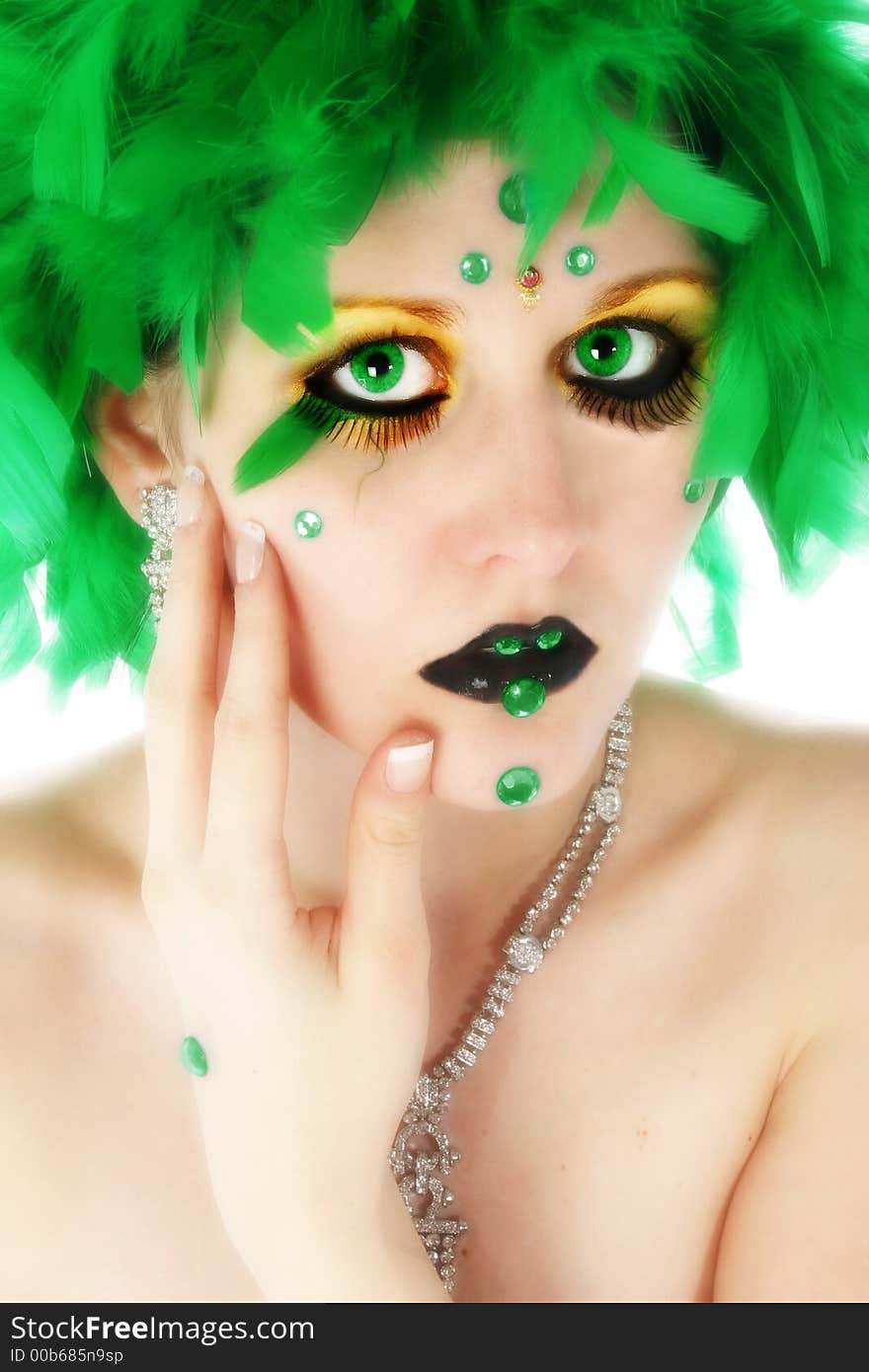 Beautiful young woman wearing artistic make-up with green feathers, beads. Beautiful young woman wearing artistic make-up with green feathers, beads.