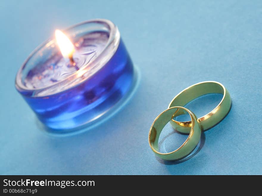 Gold wedding rings with blue burning candle. Gold wedding rings with blue burning candle