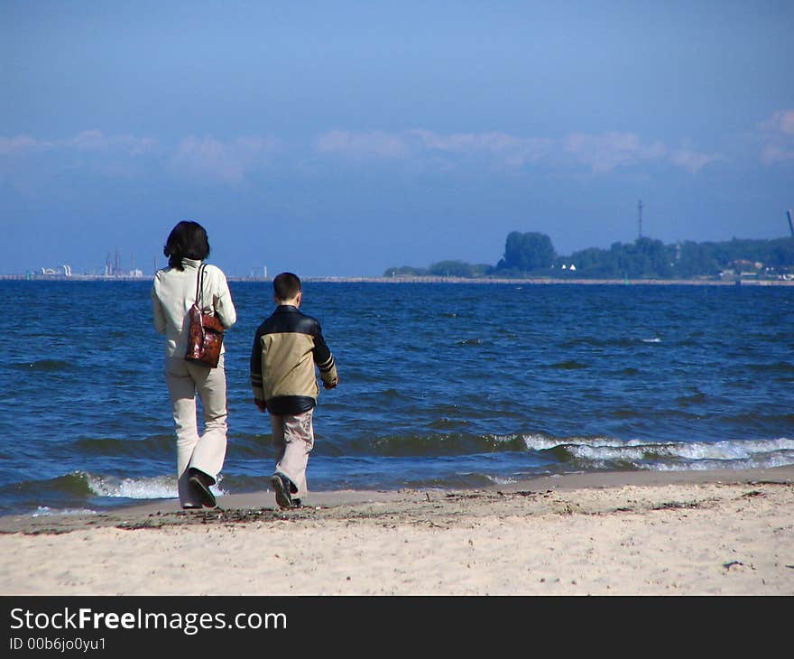 A mother and a son walking on the beach in early spring. A mother and a son walking on the beach in early spring