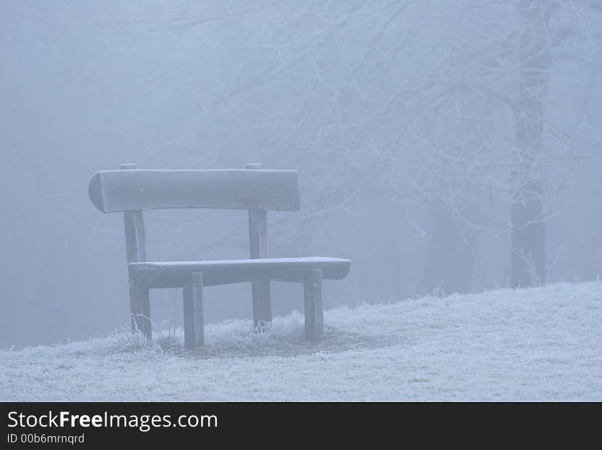 A bench and the hoarfrost-covered grass on an ice foggy day. A bench and the hoarfrost-covered grass on an ice foggy day