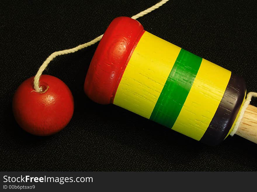 This child's ball and cup toy is perfectly set against a black background. This child's ball and cup toy is perfectly set against a black background.