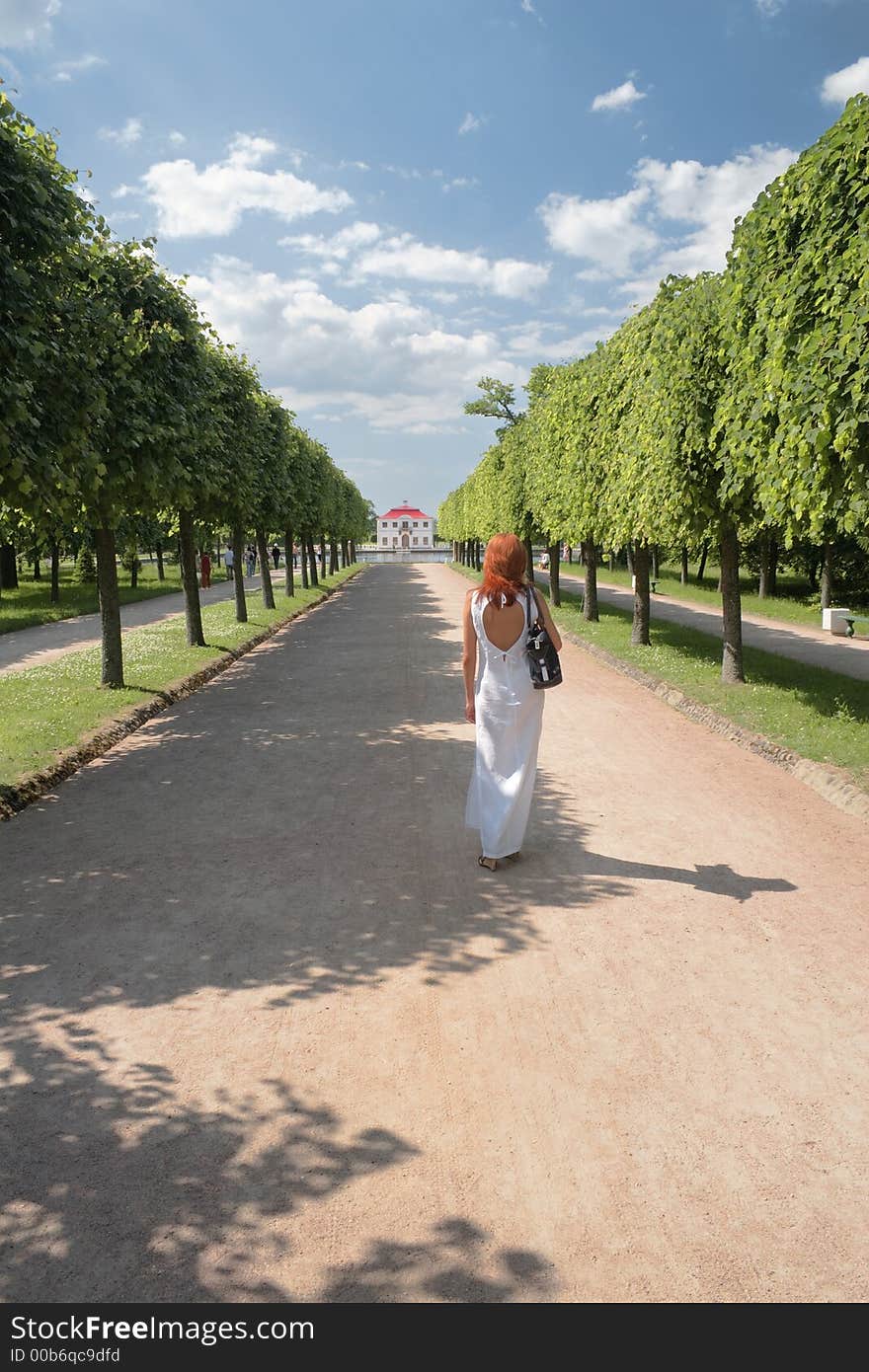 Woman in white, walking on Marli palace road in Peterhof,Russia. Woman in white, walking on Marli palace road in Peterhof,Russia