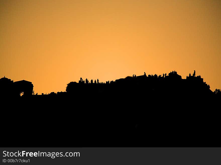 People silhouetted against the sunset along the cliff Santorini