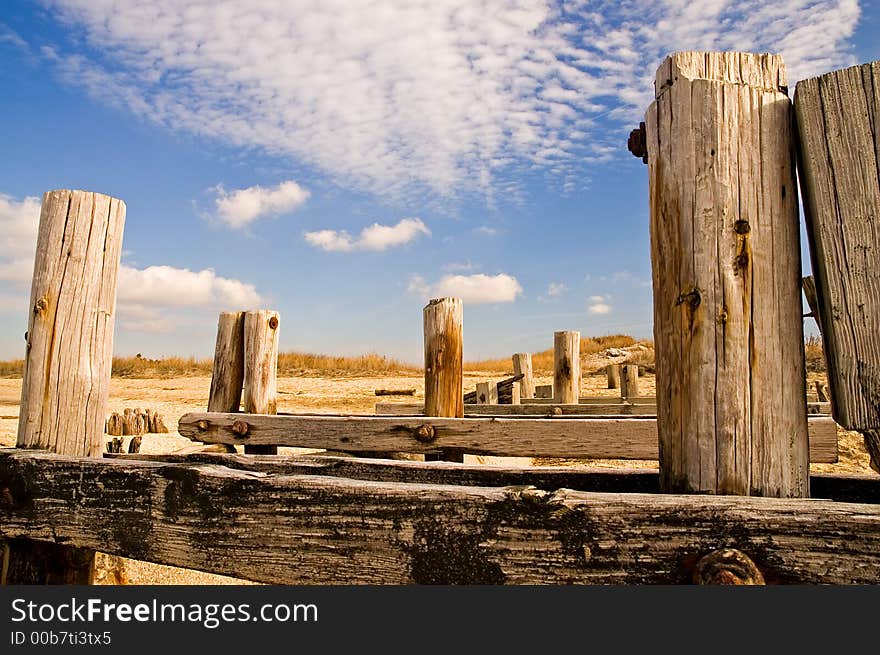 The weatherbeaten, worn remains of wooden pilings that used to support an abandoned pier and boardwalk on the beach. The weatherbeaten, worn remains of wooden pilings that used to support an abandoned pier and boardwalk on the beach.