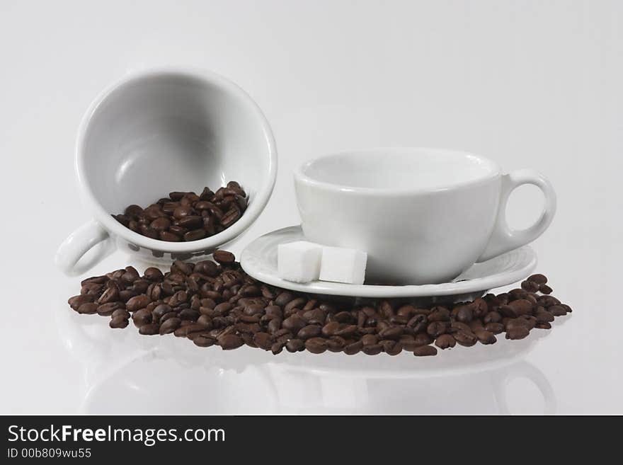 Two white cups with coffee-beans and sugar canes. Two white cups with coffee-beans and sugar canes