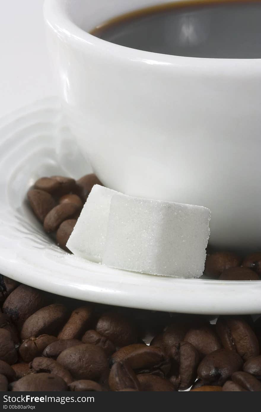 Close up of white coffee cup with coffee-beans and sugar canes. Close up of white coffee cup with coffee-beans and sugar canes