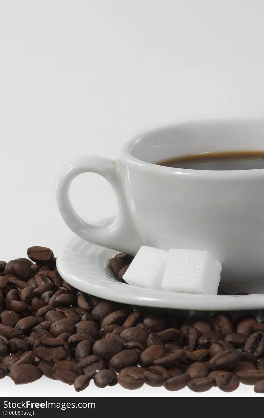 Close up of white coffee cup with coffee-beans and sugar canes. Close up of white coffee cup with coffee-beans and sugar canes