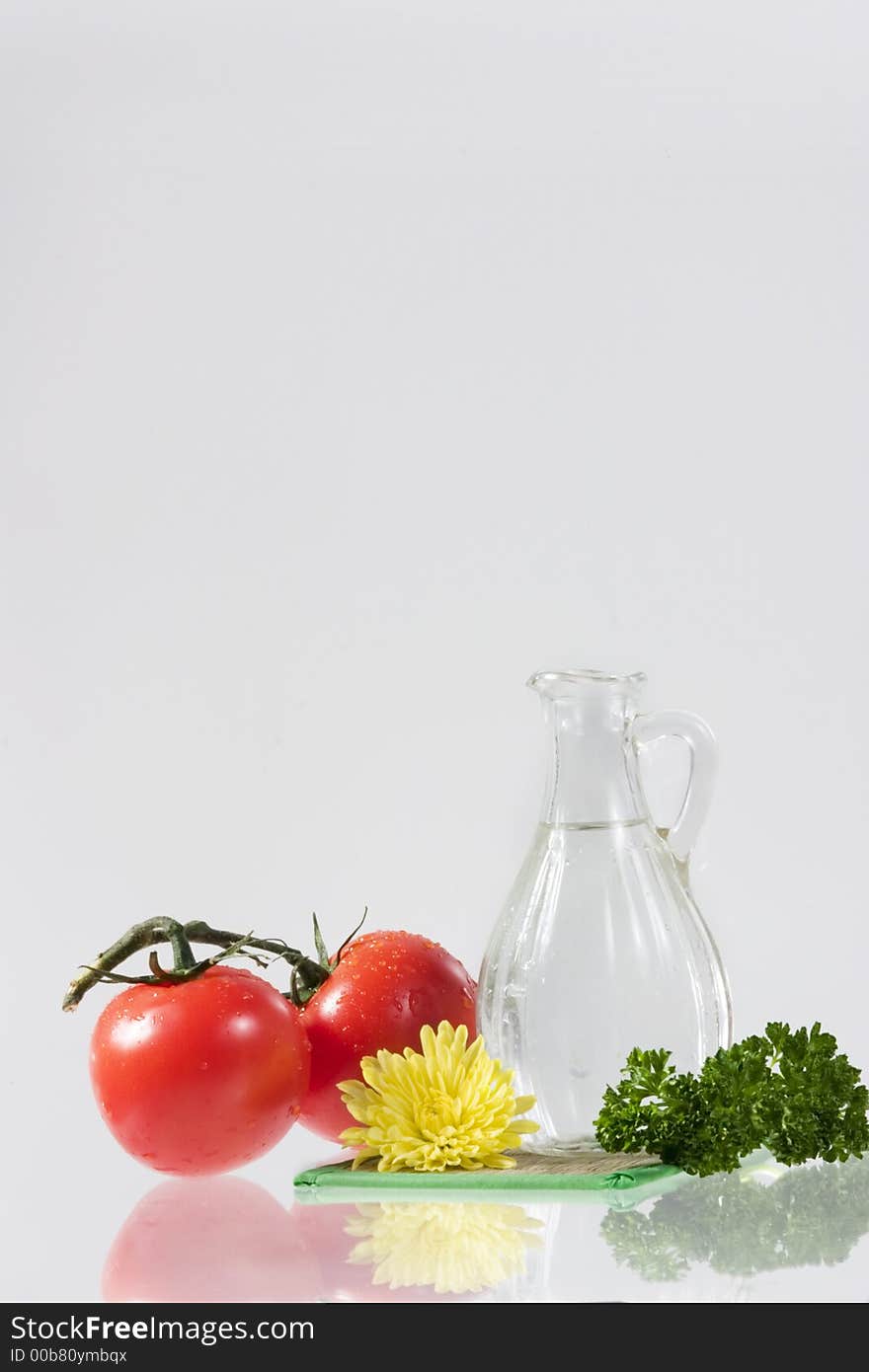 Tomatoes, yellow flower, parsley and decanter with water over white. Tomatoes, yellow flower, parsley and decanter with water over white