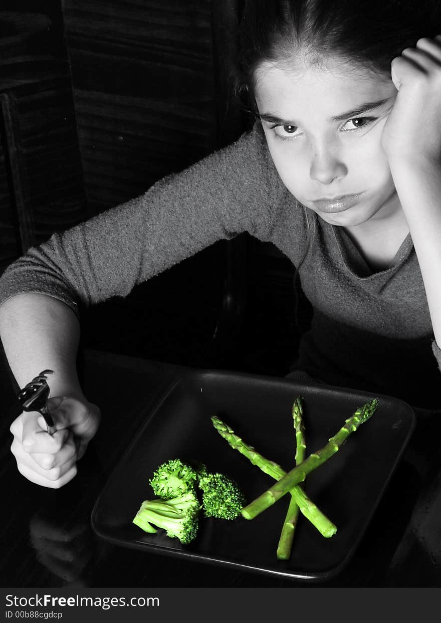 Young girl looking angry at the thought of having vegetables for dinner ~ selective Color. Young girl looking angry at the thought of having vegetables for dinner ~ selective Color.