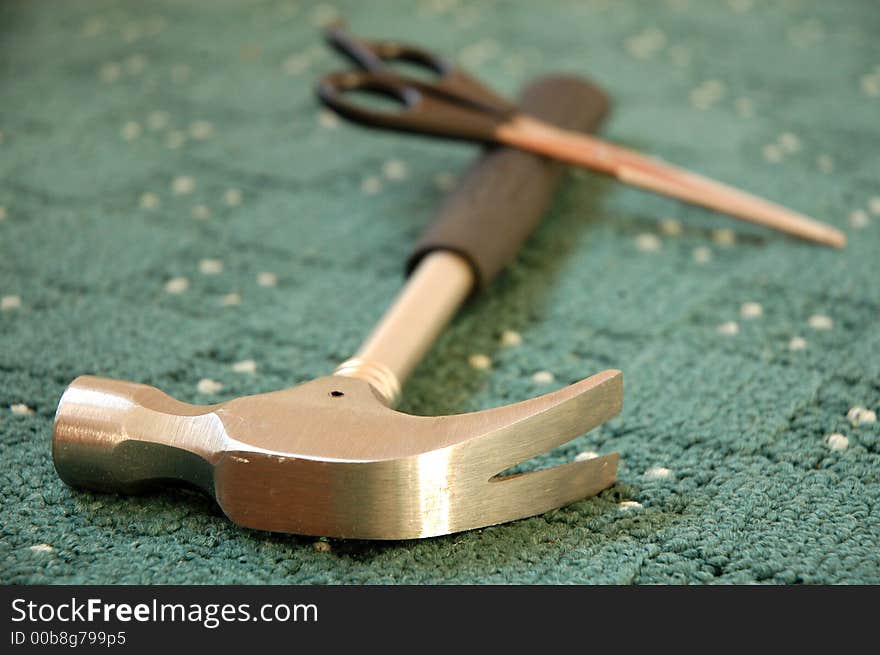 Scissors and hammer lying on new green carpet