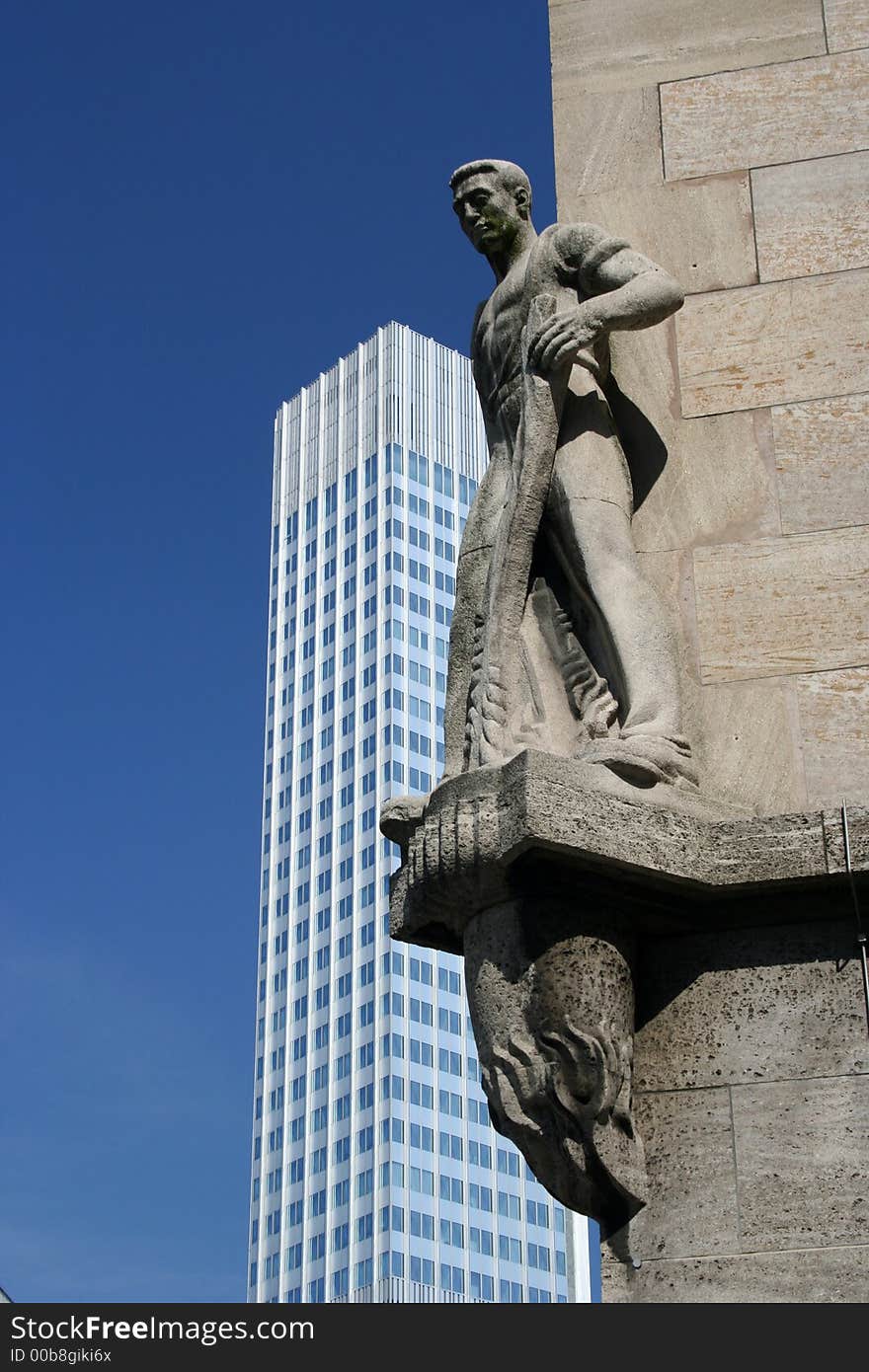 The sculpture in front of the modern building.