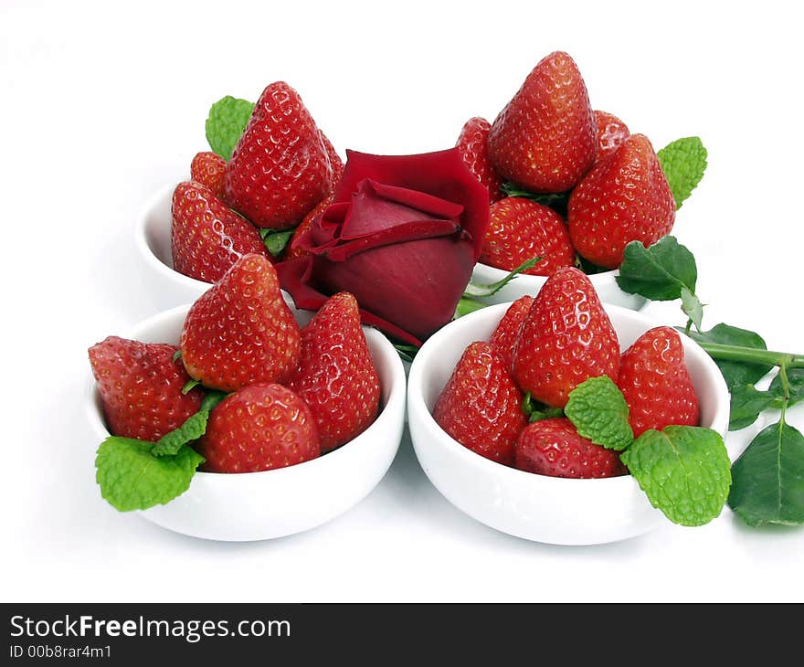 Some strawberry little bowls with mint on white background and one valentine rose