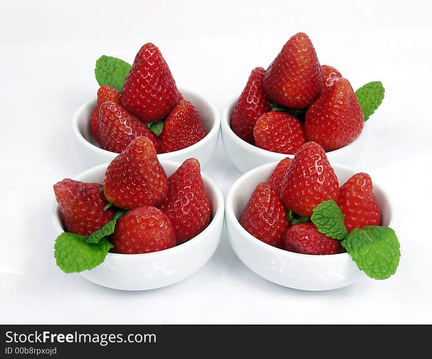 Some strawberry little bowls with mint on white background