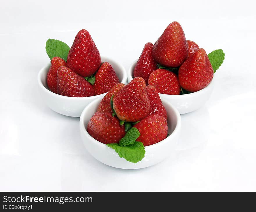 Some strawberry little bowls with mint on white background