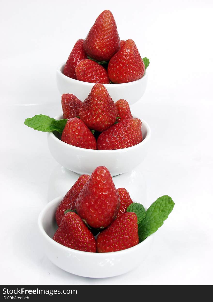 Some strawberry little bowls with mint on white background