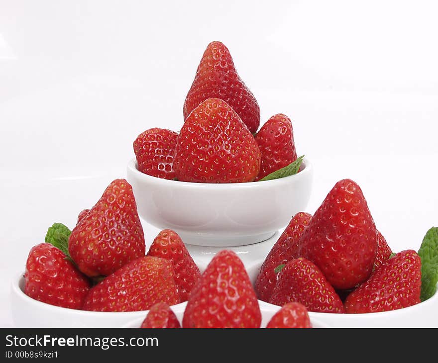 Some strawberry little bowls with mint on white background