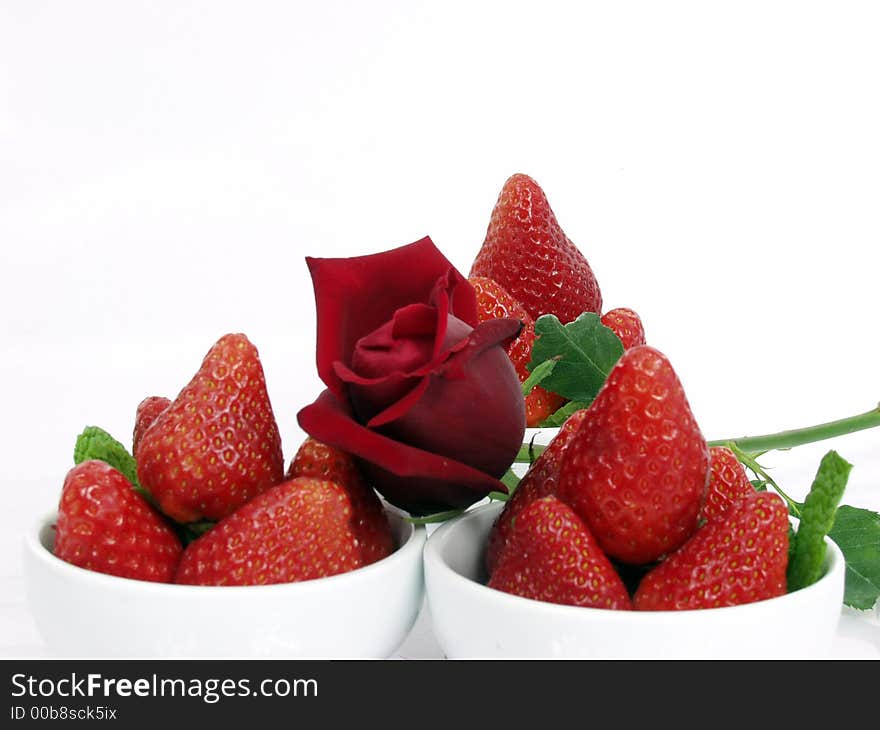 Some strawberry little bowls with mint on white background and one valentine rose