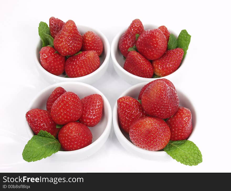 Some strawberry little bowls with mint on white background