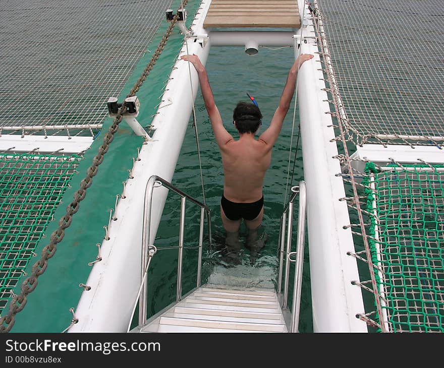 Snorkeling man at water on catamaran