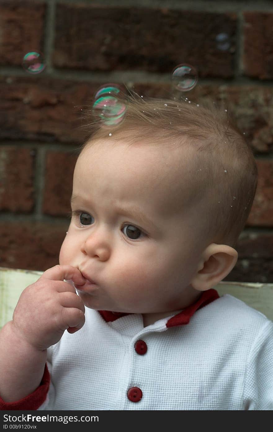 Image of baby boy sitting on a chair surrounded by soap bubbles. Image of baby boy sitting on a chair surrounded by soap bubbles