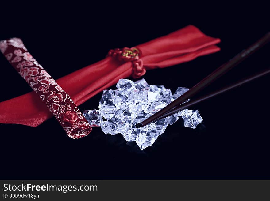 A pile of uncut diamonds on black satin with traditional chopsticks and oriental motif. A pile of uncut diamonds on black satin with traditional chopsticks and oriental motif