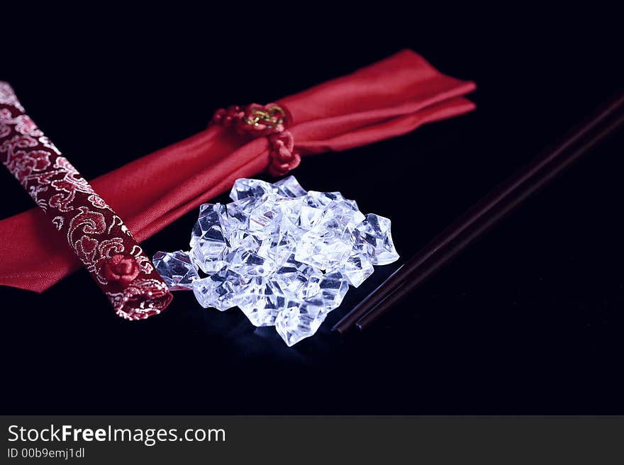 A pile of uncut diamonds on a black silk mat with chopsticks and an oriental flair. A pile of uncut diamonds on a black silk mat with chopsticks and an oriental flair.