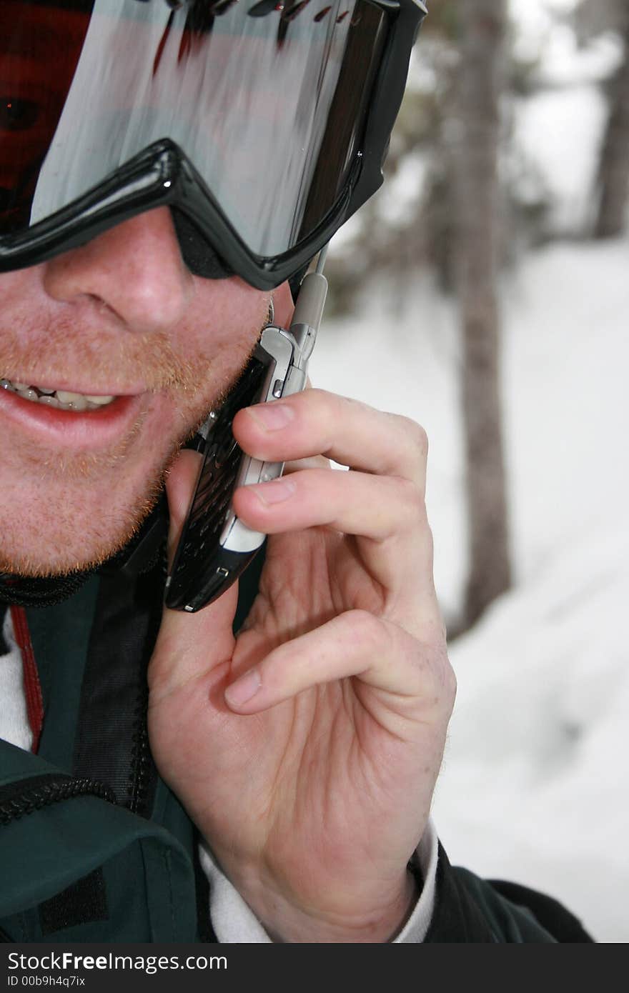 A man uses his cell phone while enjoying the outdoors skiing #3. A man uses his cell phone while enjoying the outdoors skiing #3