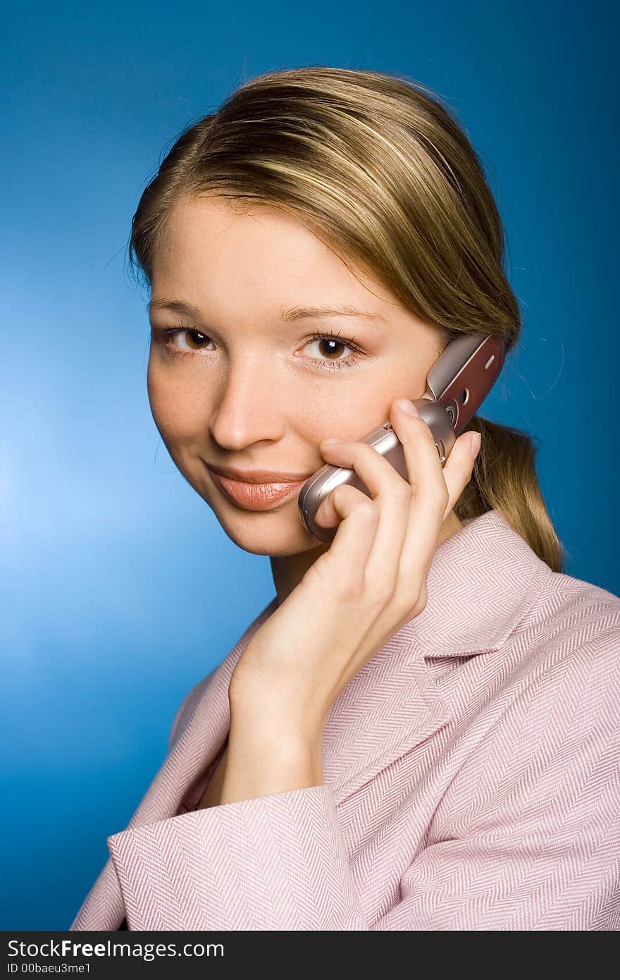 Young woman with mobile phone, blue background in studio. Young woman with mobile phone, blue background in studio