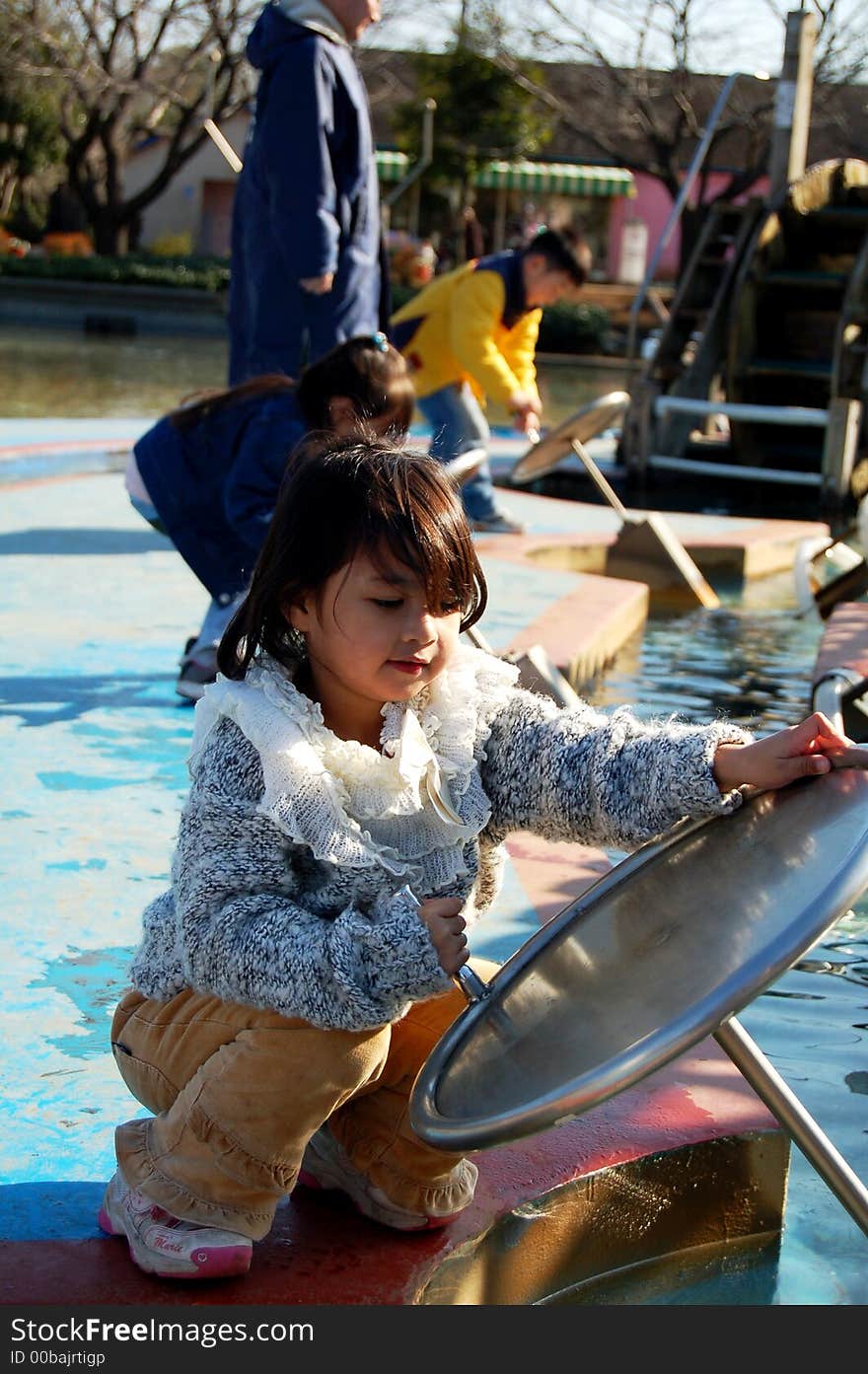 A young asian girl trying water pump at recreation park. A young asian girl trying water pump at recreation park.