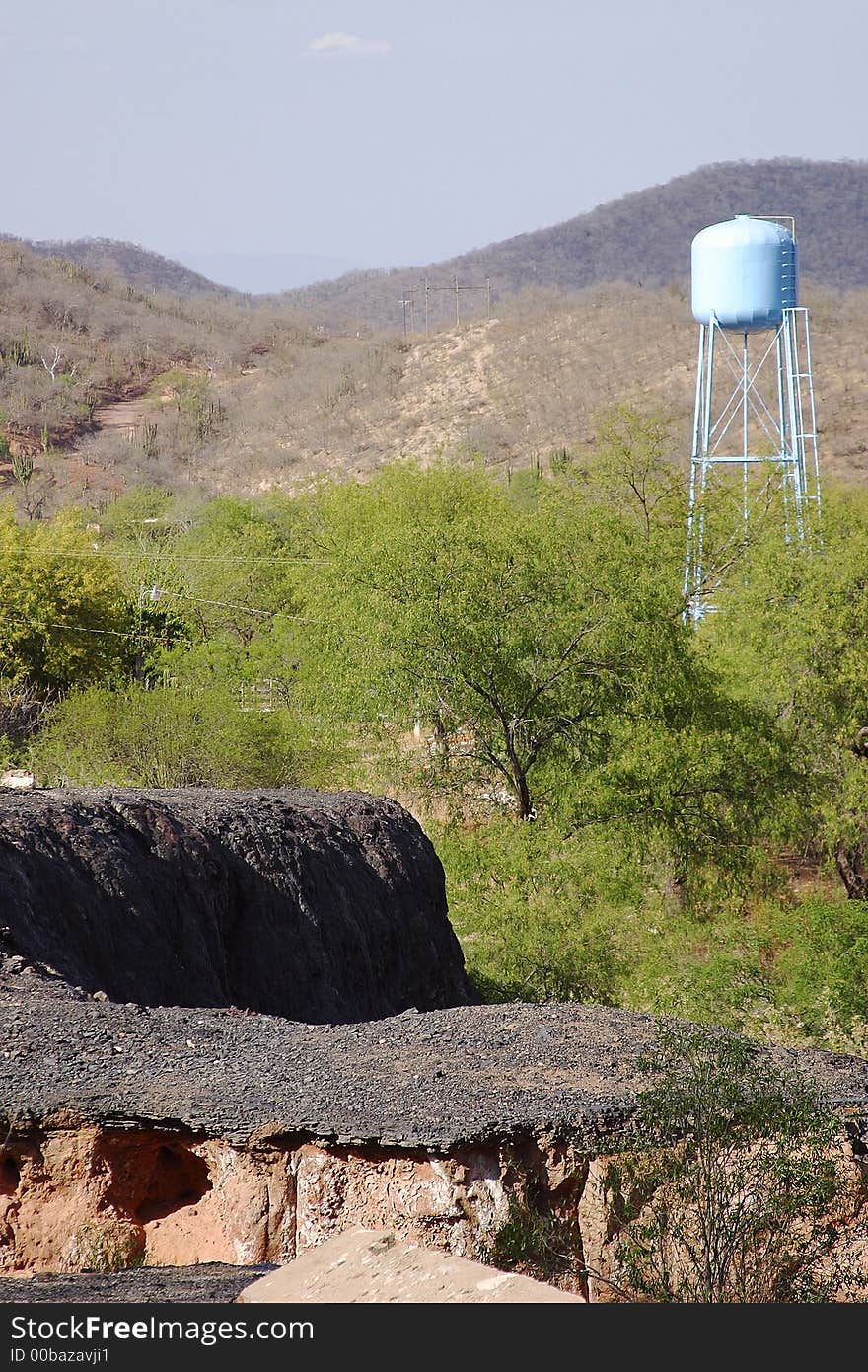 Abandoned road and water tank in the back in front of the foothill of the Sierra Madre in the town of Alamos, in the northern state of Sonora, Mexico, Latin America