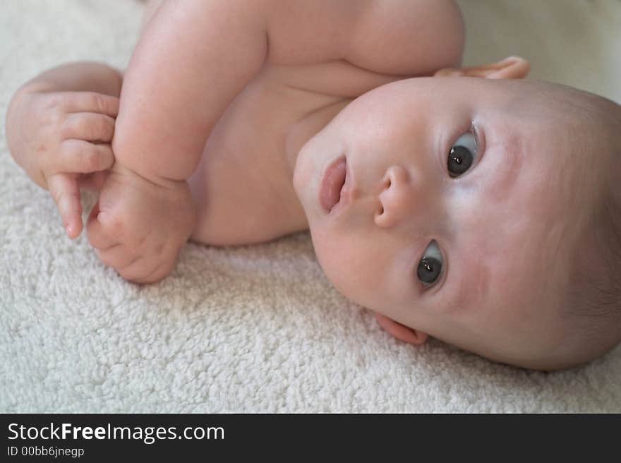 Image of baby boy lying down on a blanket, looking at the camera. Image of baby boy lying down on a blanket, looking at the camera