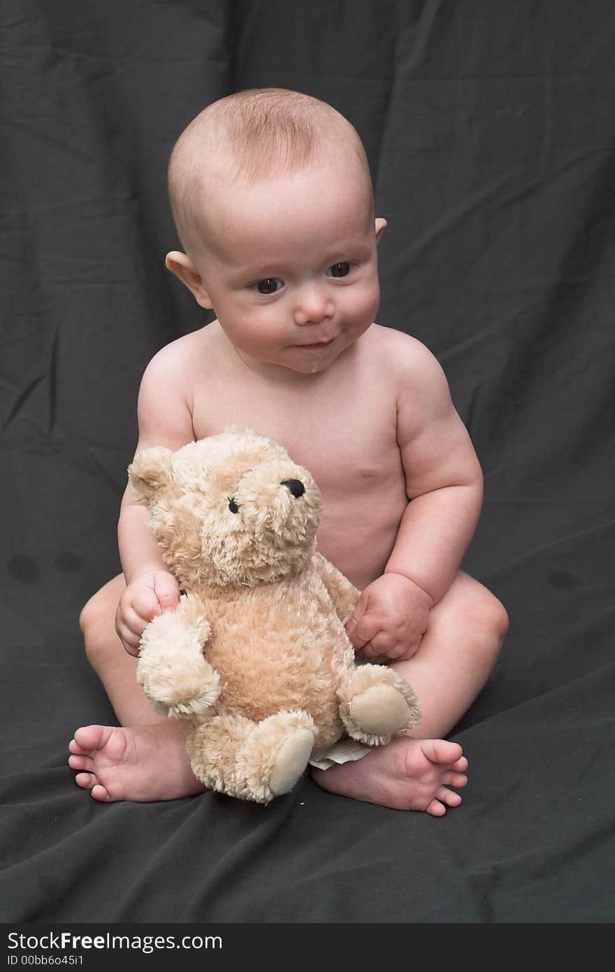 Image of baby boy sitting up holding a teddy bear. Image of baby boy sitting up holding a teddy bear