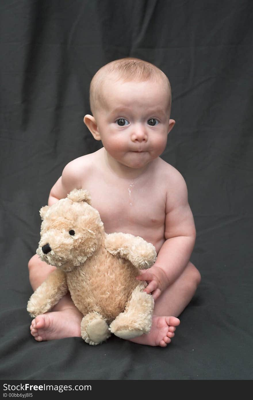 Image of baby boy sitting up holding a teddy bear. Image of baby boy sitting up holding a teddy bear