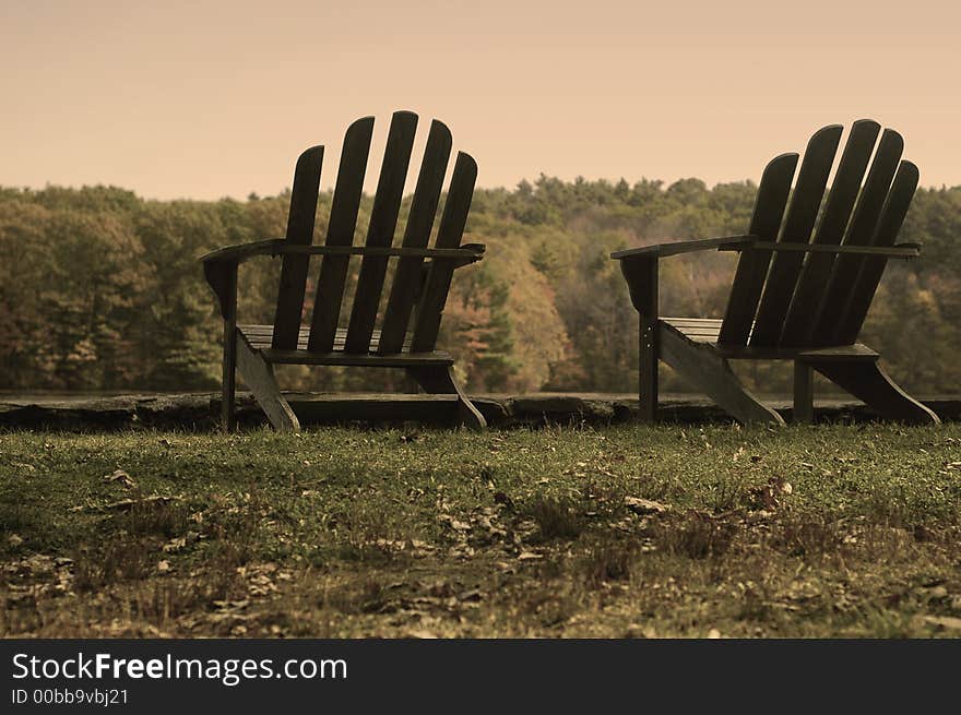 Taken at a state park in Massachusetts, USA. Made to look aged and old with a sepia filter over color, not black and white. Two adirondack chairs in a grassy scene. Taken at a state park in Massachusetts, USA. Made to look aged and old with a sepia filter over color, not black and white. Two adirondack chairs in a grassy scene.