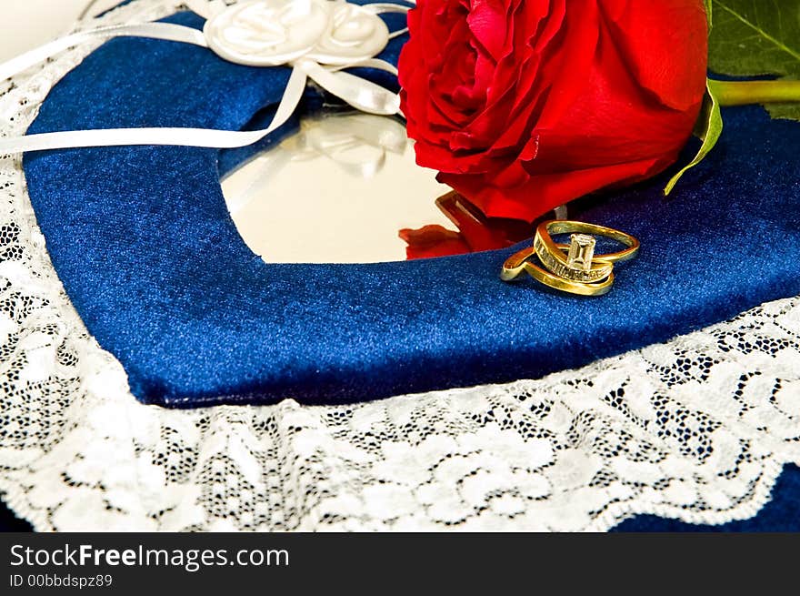 Beautiful engagement and wedding rings and a perfect red rose sit on a lacy, blue wedding photo album. Valentines Special!. Beautiful engagement and wedding rings and a perfect red rose sit on a lacy, blue wedding photo album. Valentines Special!