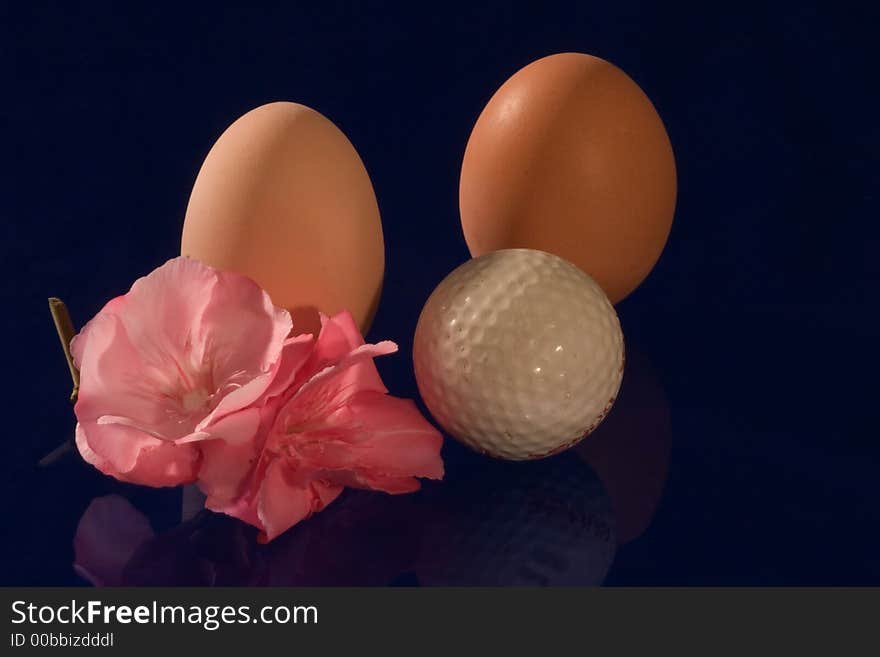 Eggs with golf ball and azalea flower on dark blue background