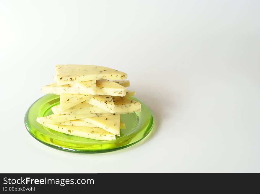 Sliced cheese on the green plate close-up