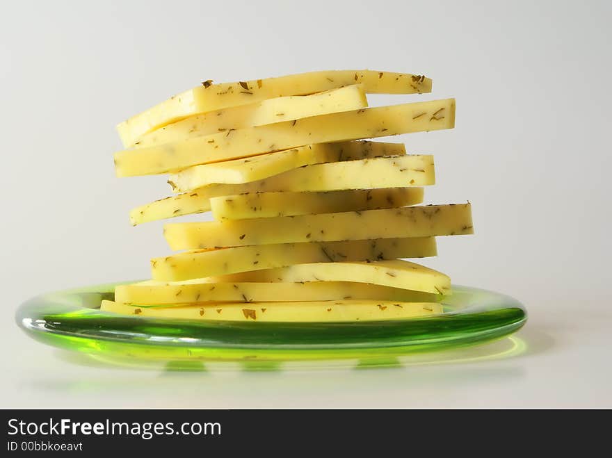 Sliced cheese on the green plate close-up